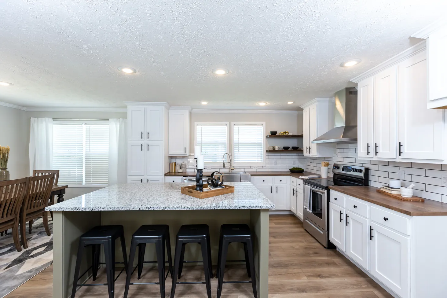 Large kitchen with white cabinets, brown countertops, and an island with black-and-white speckled countertop
