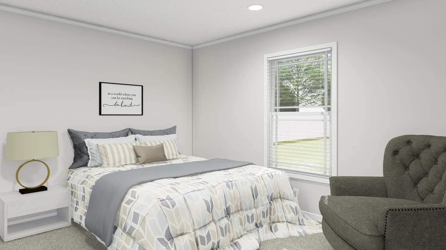 Bedroom with side table and lamp, chair, patterned bedspread, and a framed quote picture above the bed