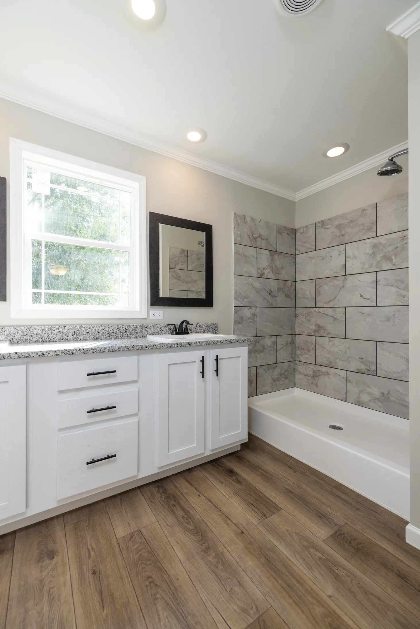 Clean, modern bathroom with white cabinets and a marble textured wall.