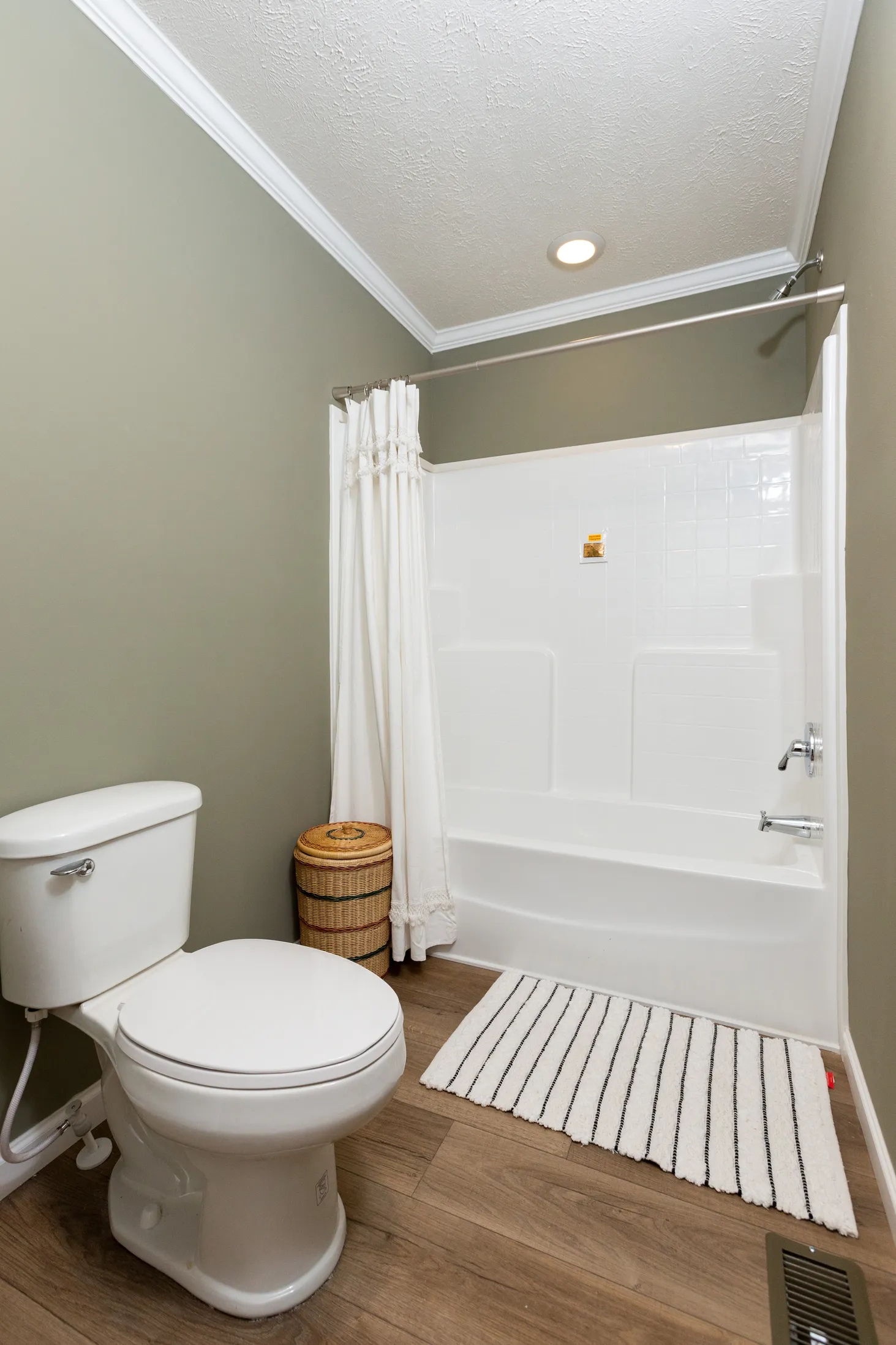 Small bathroom with bathtub-shower combo, plain white backsplash, and green walls