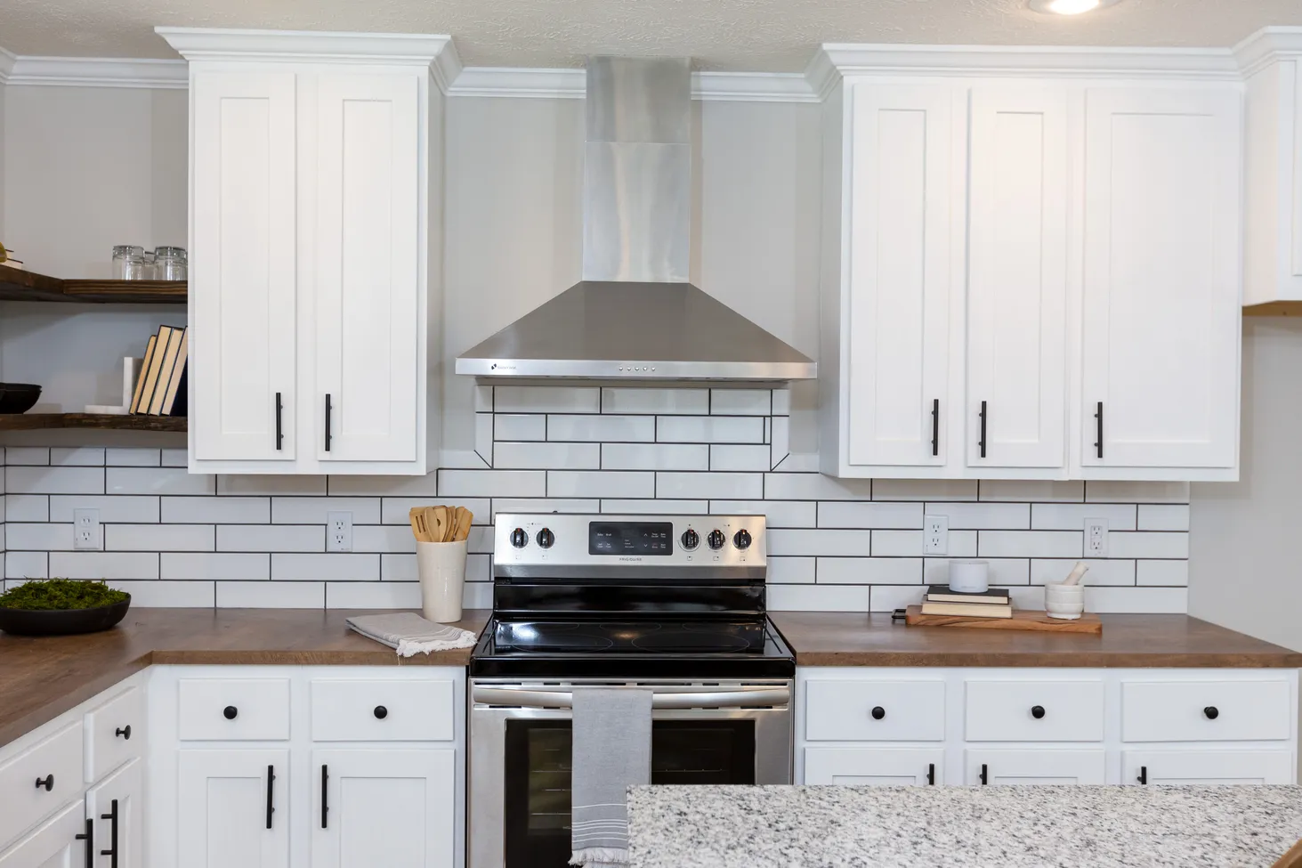 Close-up view of kitchen with brown countertops and white cabinets and drawers