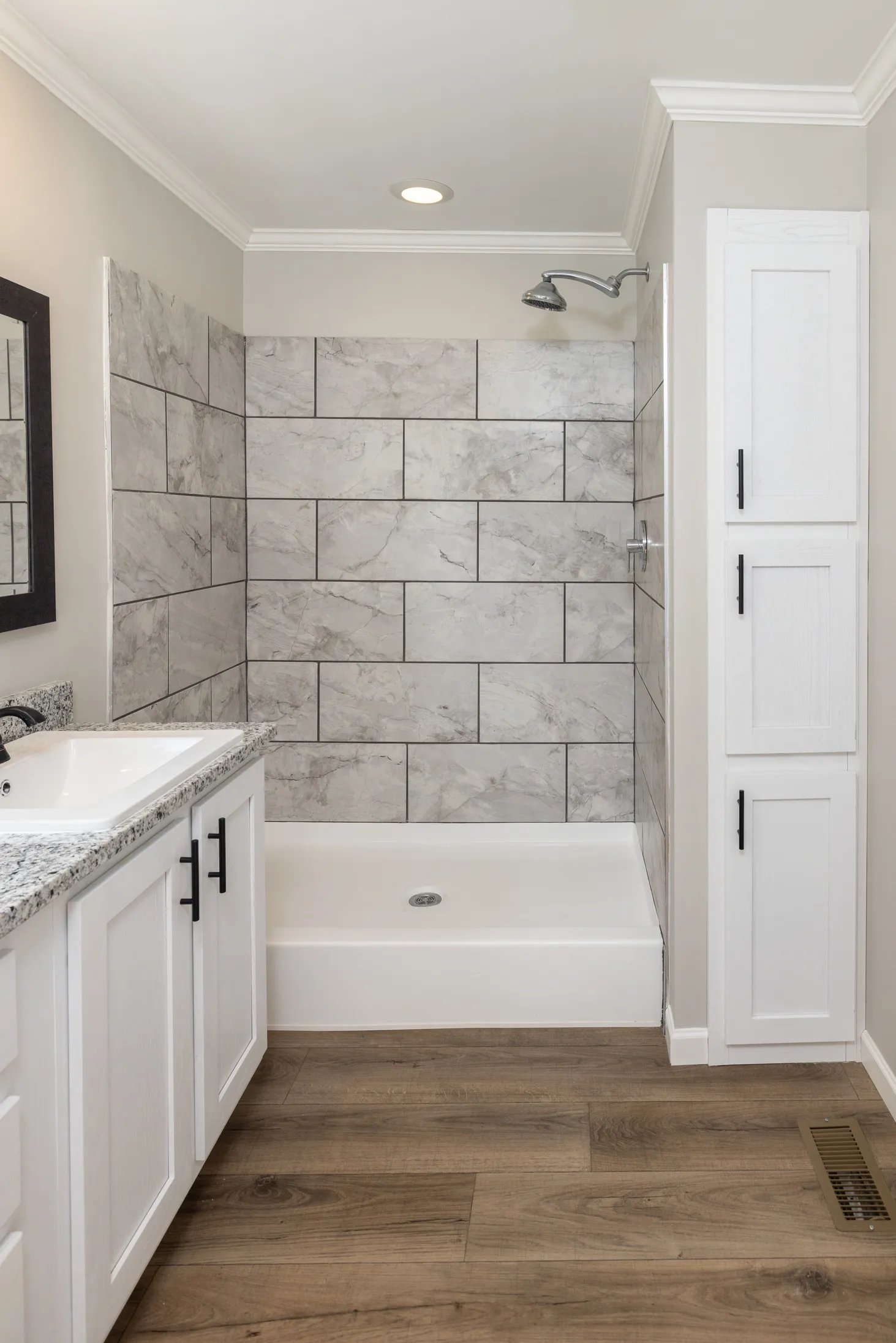 Side view of bathroom focusing on shower with marble backsplash