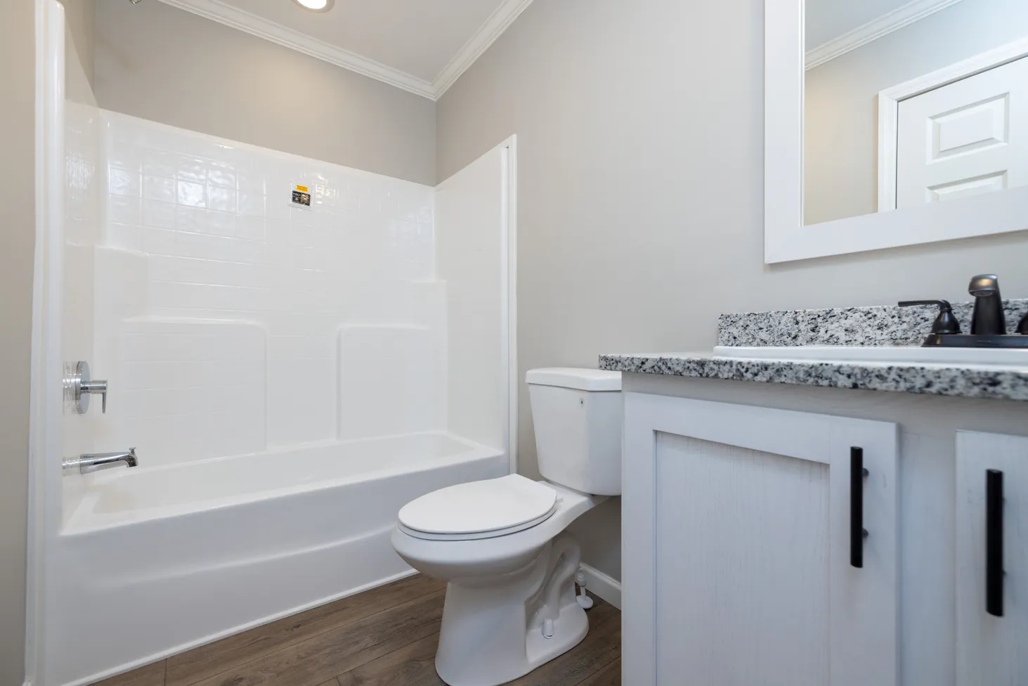 Full bathroom with white back-splashed shower and white-and-black speckled sink