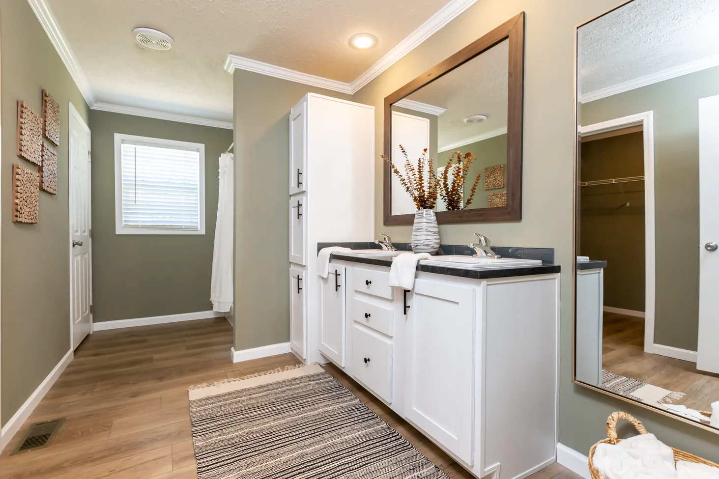 Long bathroom with green walls and double sinks on a medium-sized countertop