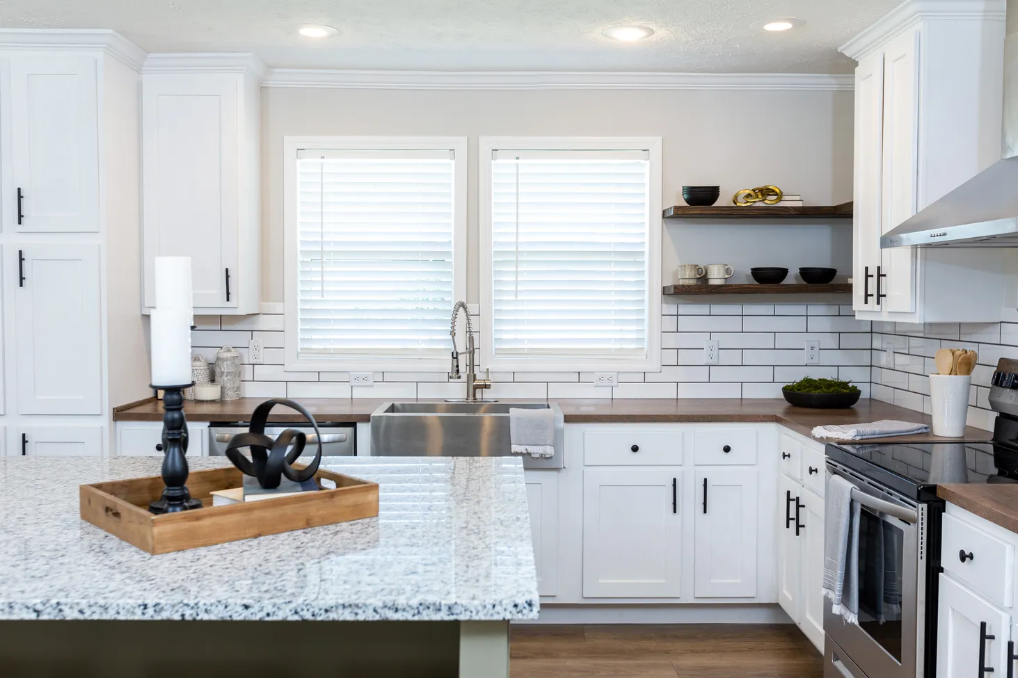 Large kitchen with white cabinets, brown countertops, and an island with black-and-white speckled countertop