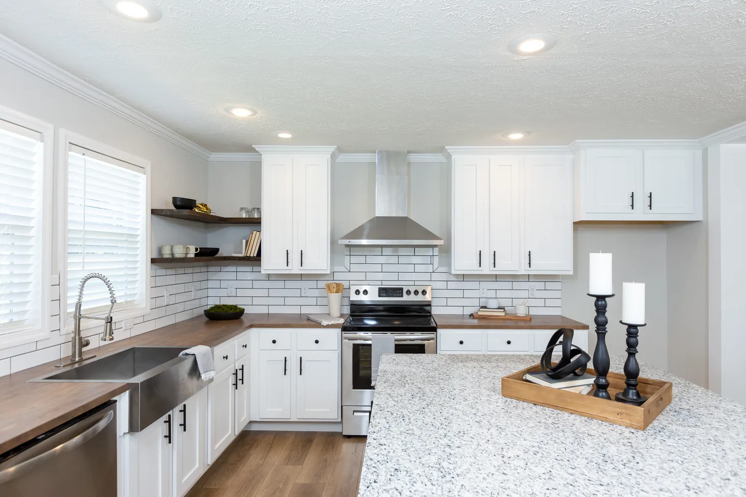 Large kitchen with white cabinets, brown countertops, and an island with black-and-white speckled countertop