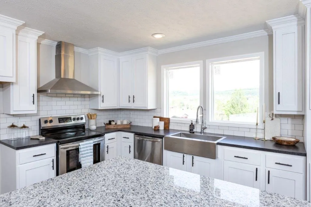 Close-up of kitchen with white cabinets, drawers, and white brick backsplash