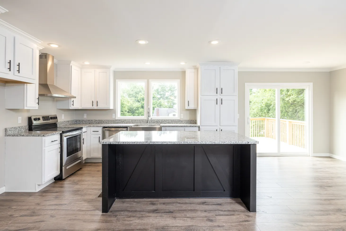 Modern kitchen with island, black-and-white speckled countertops, and white cabinets and drawers