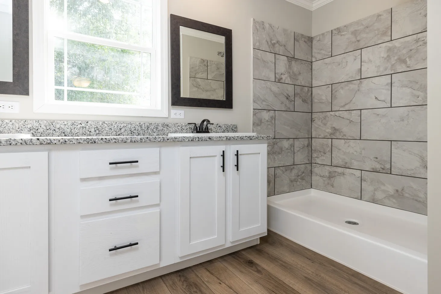 Clean, modern bathroom with white cabinets and a marble textured wall.