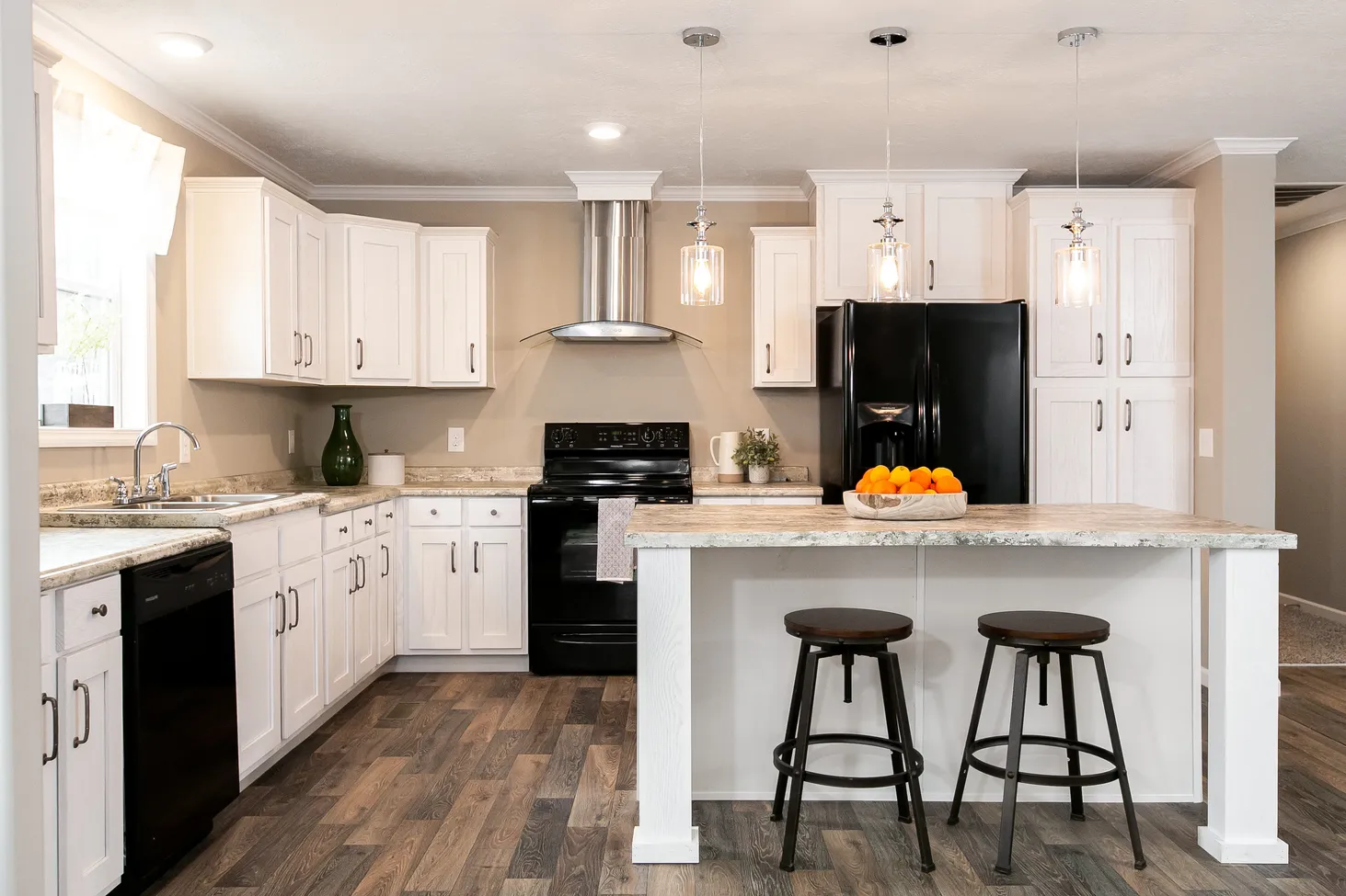 Large kitchen with black appliances and an island fitting two stools